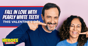 A pair of smiling people point at their own mouths.