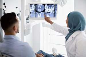 A dentist pointing to an x-ray of a tooth's root.